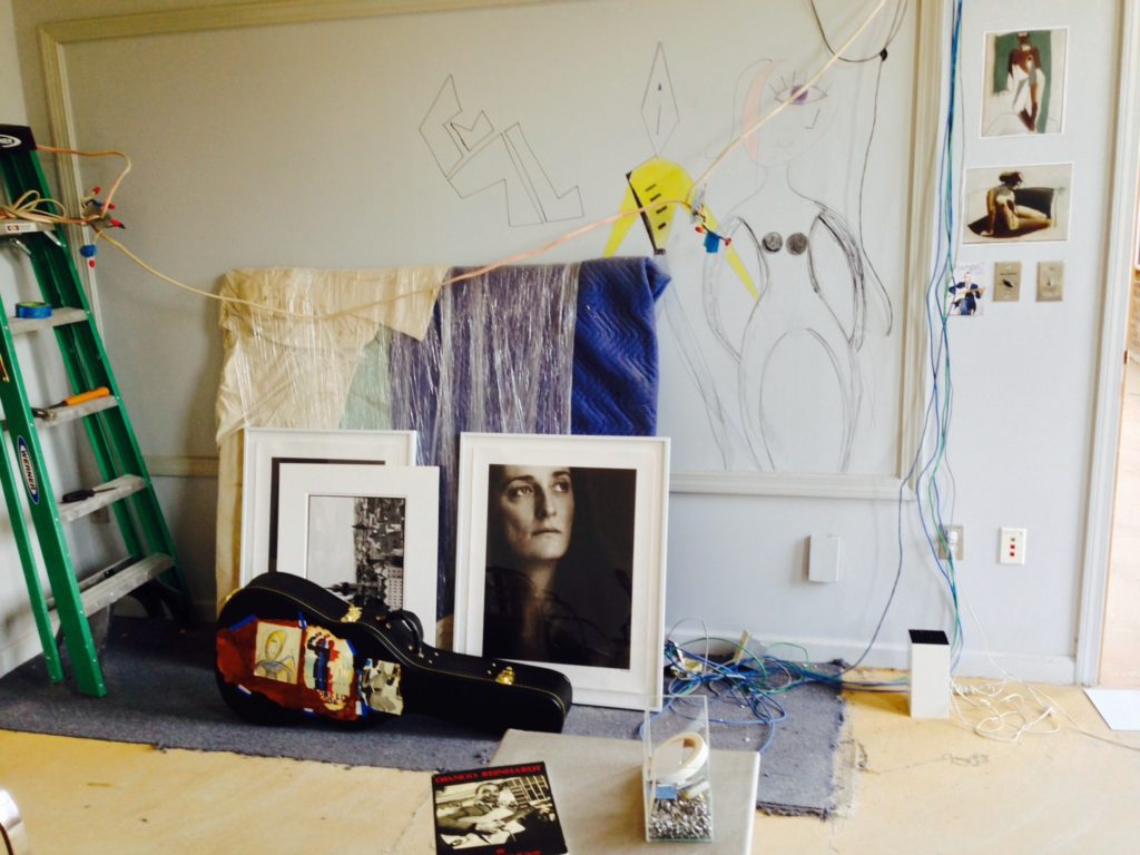 Paul Ickovic's studio, showing framed photographic prints, sketches on the wall, a ladder, wires, and tools & fittings 